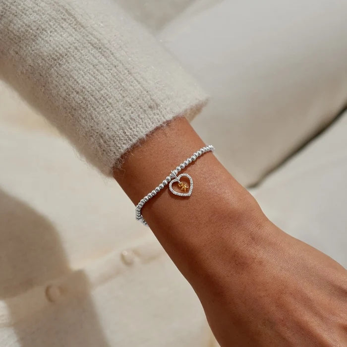 A Littles & Co. A Little Best News Ever bracelet worn on wrist with silver beaded band and heart charm featuring gold star detail
