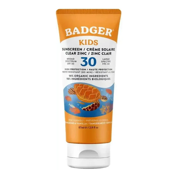 A tube of Badger Kids sunscreen, shade Clear Zinc, featuring an orange and white design with a blue underwater illustration of a sea turtle and fish. The text is printed in English and French.