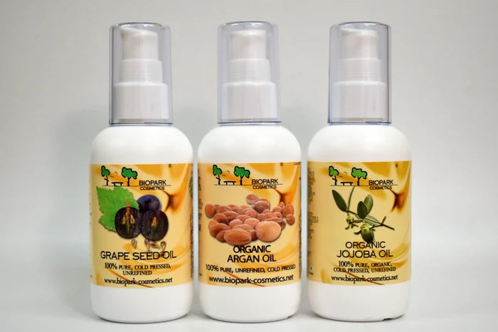 Three bottles of organic oils with visible labels on a gray background