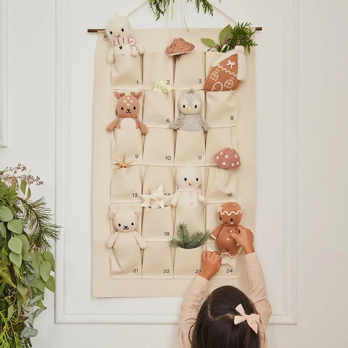 Advent calendar display with hand-knit holiday dolls including baby snowman, gingerbread, bear, penguin, and fawn.