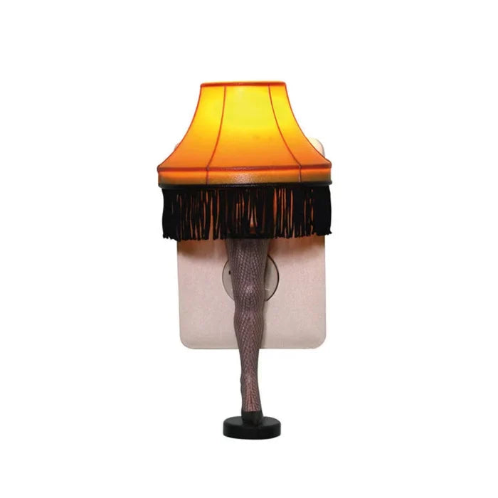 Novelty lamp with a yellow shade and black fringe, resembling legs wearing fishnet stockings night light on a white background.