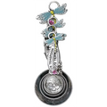 Decorative spoon with dragonfly designs and floral elements on a white background