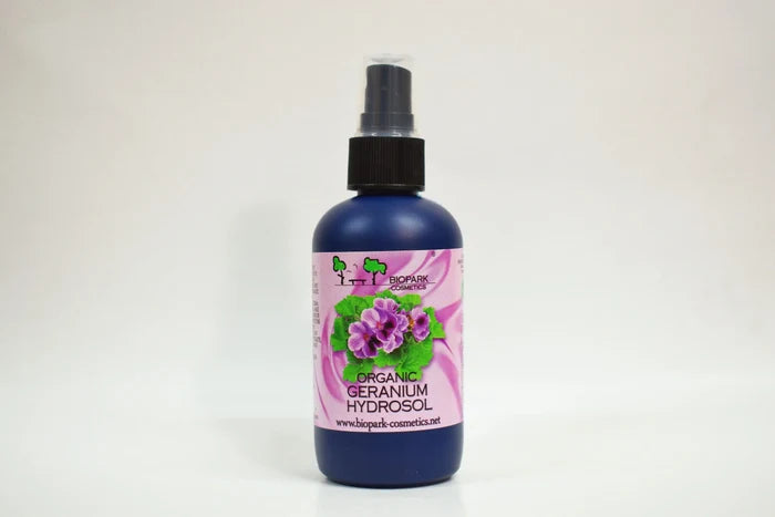 Bottle of organic geranium hydrosol with a pink label on a white background