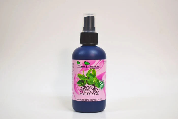 Bottle of organic green tea hydrosol with a pink label on a white background
