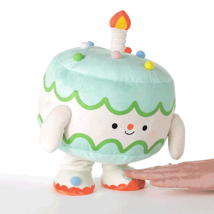 Plush birthday cake lifestyle showing a hand activating motion and and sound