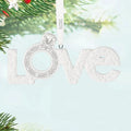 Decorative ornament with 'LOVE' and a ring design, hanging on a tree.
