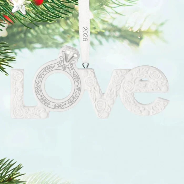 Decorative ornament with 'LOVE' and a ring design, hanging on a tree.