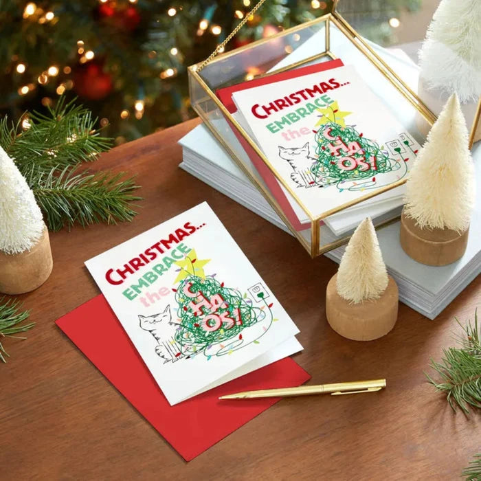 Christmas cards with festive designs on a wooden table with decorative elements.