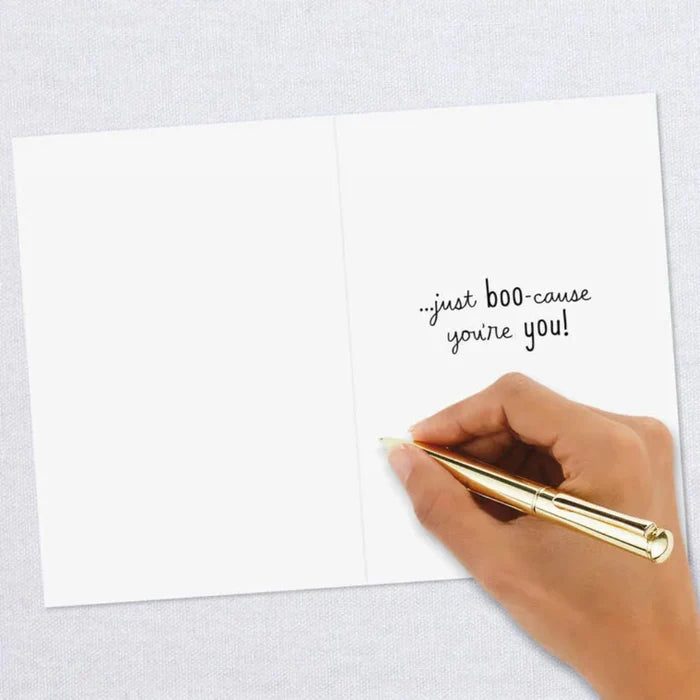 Hand holding a gold pen over a white card with text on a light gray background