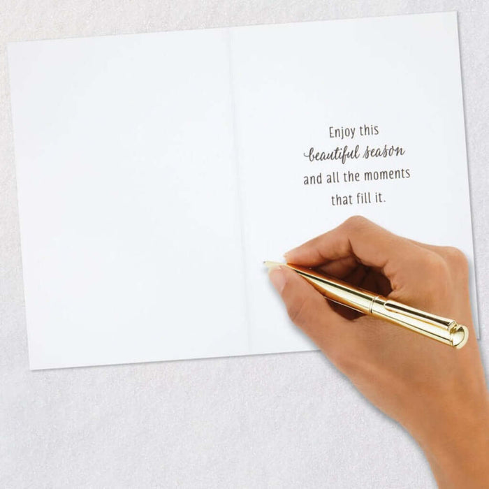 Hand holding a gold pen over a white card with a message on a light gray background