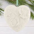 Heart-shaped ceramic ornament with floral patterns hanging on a branch.