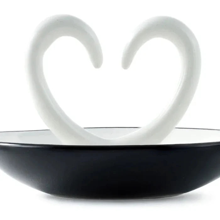 close up of Ring dish ceramic with arms that shape a heart. trinket dish on a white background.