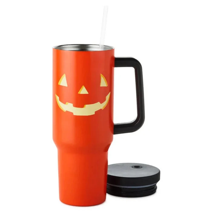 Orange travel mug with a jack-o'-lantern face design, showing straw and lid of tumbler on a white background