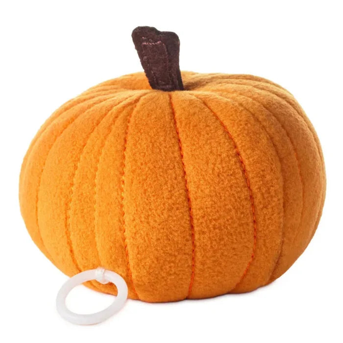 Plush pumpkin toy with a white tag on the backside of toy, on a white background