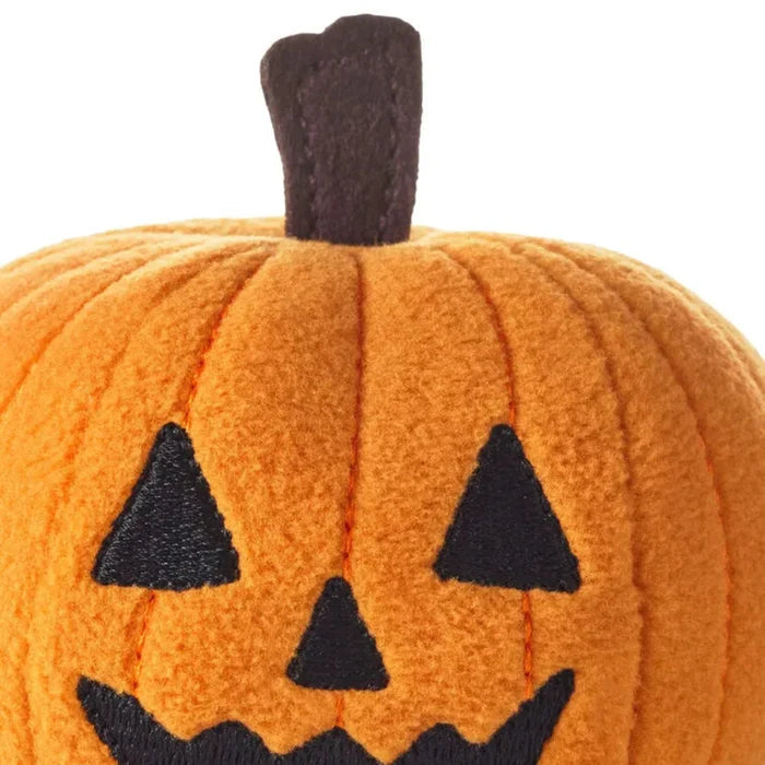Closeup of Hallmark Fuzzy orange pumpkin with black triangular eyes and mouth on a white background