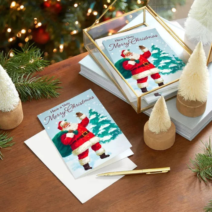 Stack of Christmas cards with Santa Claus design on a wooden surface with festive decorations.
