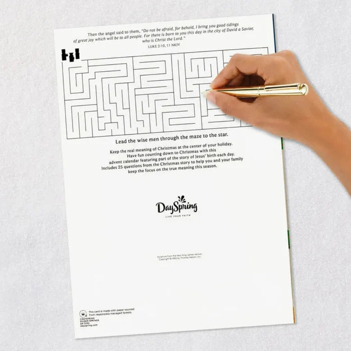 Back side of advent calendar Hand holding a pen over a maze puzzle with DaySpring branding on a white background.