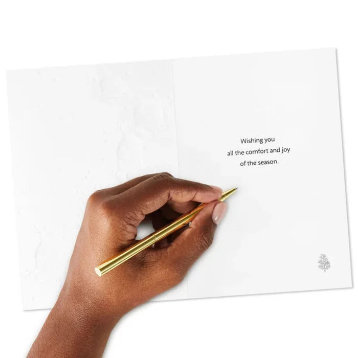 Hand holding a gold pen over a greeting card with a message on a white background