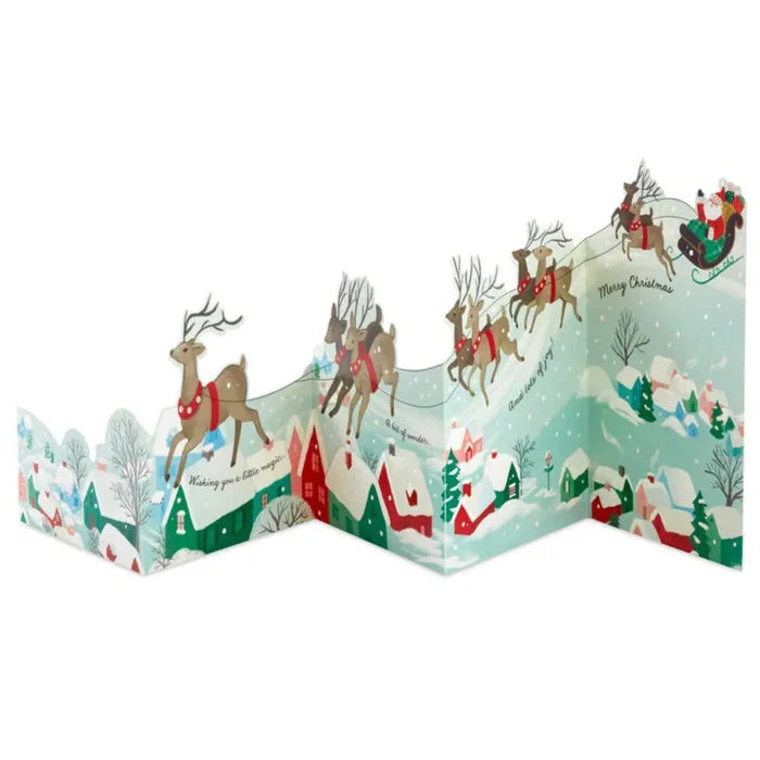 Christmas-themed pop-up card with reindeer and Santa Claus in a snowy village scene.