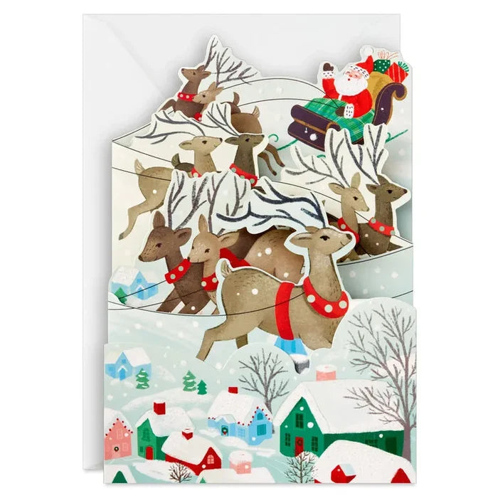 Christmas card with reindeer and Santa Claus in a snowy village scene