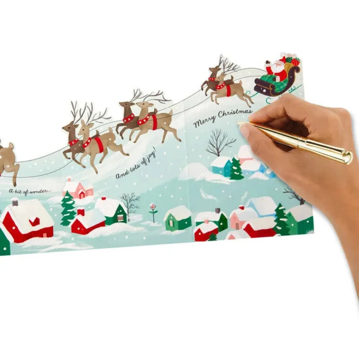 Christmas-themed stationery set with Santa Claus and reindeer design, held by a hand with a pen.