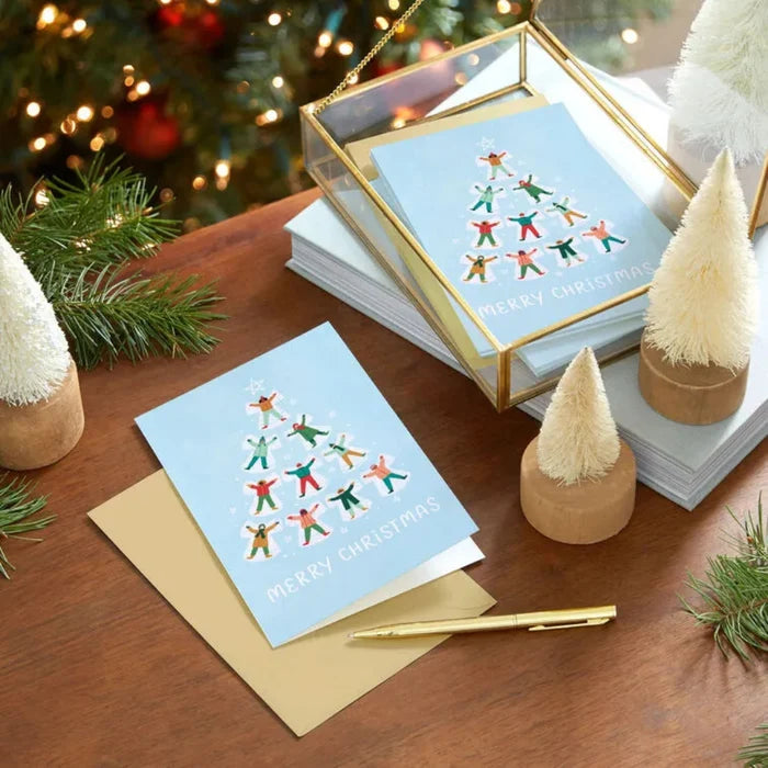 Stack of Christmas cards with a tree design on a wooden surface with decorative elements.