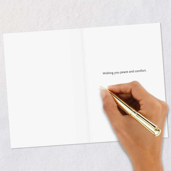 Hand holding a gold pen over a white card with text on a light gray background
