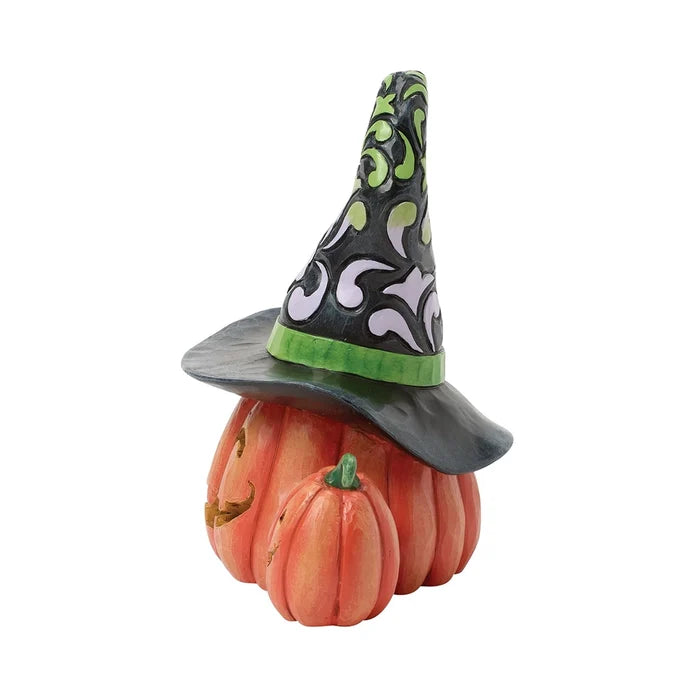 arved pumpkin jack-o’-lantern wearing a tall patterned witch hat with green band and dangling spider accent.