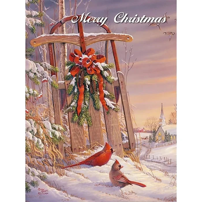 Christmas card with two cardinals, a sled with a wreath, and a snowy village scene.