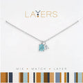 A close-up of a layered necklace set on a striped background, showcasing its elegant style and multiple strands.