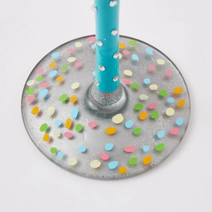 Decorative wine glass base with colorful confetti pattern and a blue straw on a white background
