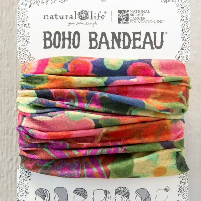 A vibrant floral print scarf displayed on a wall, showcasing a variety of colorful flowers against a light background.