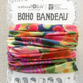 A vibrant floral print scarf displayed on a wall, showcasing a variety of colorful flowers against a light background.