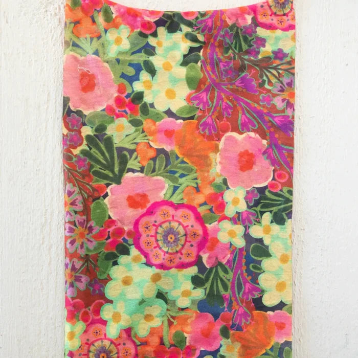 A colorful scarf with a floral pattern hanging on a wall, featuring an array of bright flowers in various shades.