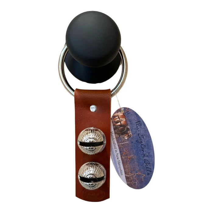 Keychain with black ball, brown leather strap, silver bells, and a purple tag on a white background