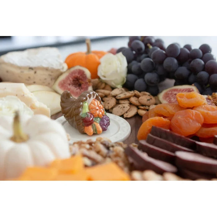 Assorted fruits, cheeses, and dried fruits on a platter with decorative elements.
