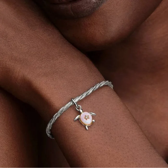 Close-up of a person's wrist wearing a bracelet with a turtle charm.