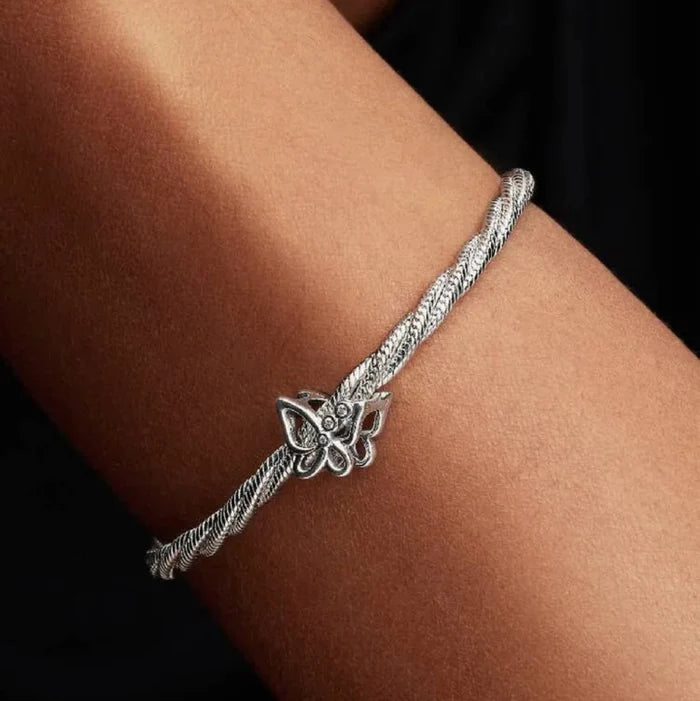 Silver bracelet with a leaf design on a wrist against a dark background