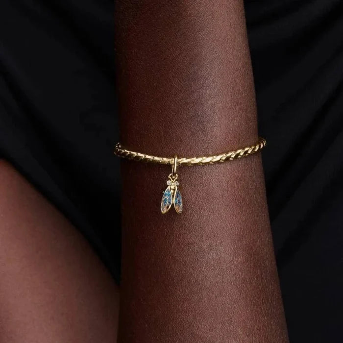 Gold bracelet with a cicada-shaped charm on the wrist