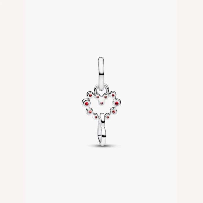 Silver heart charm with red stones on a light background