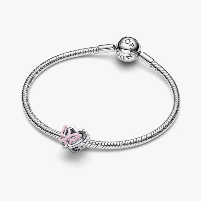 Silver heart and butterfly shaped charm on a light background