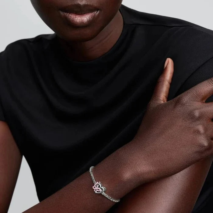 Silver bracelet with a heart and butterfly shaped charm on the wrist of a women