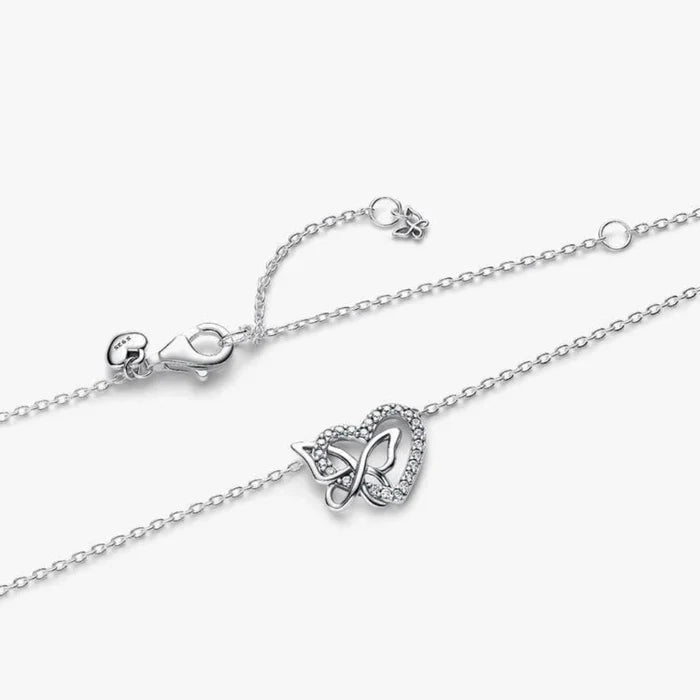 Silver necklace with a heart and butterfly shaped charm on a white background
