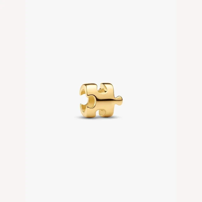 Gold puzzle piece charm on a light background