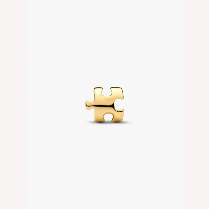 Gold puzzle piece charm on a light background