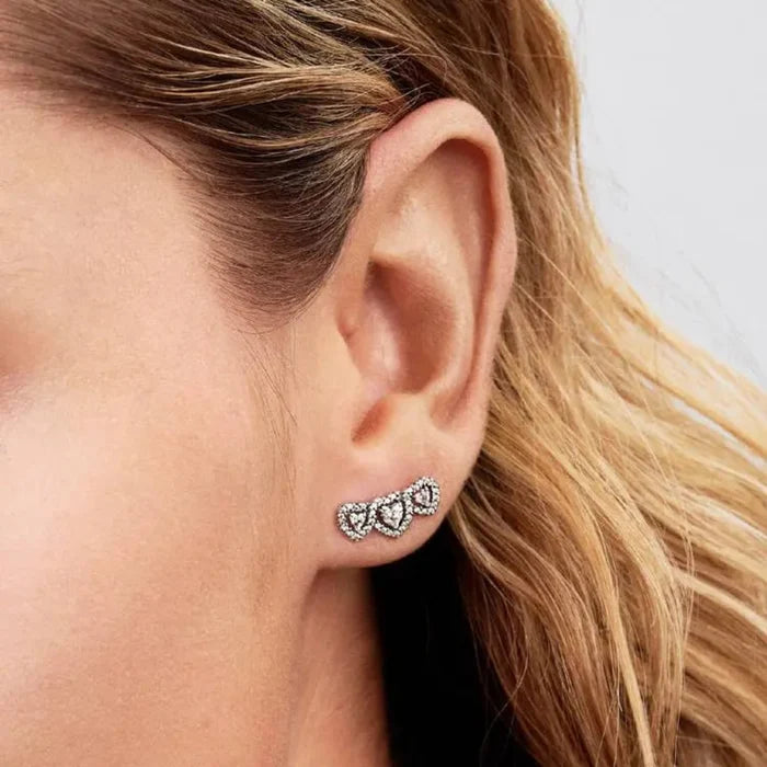 Close-up of a woman’s ear wearing the Pandora Halo Heart Trilogy Stud Earrings in sterling silver.