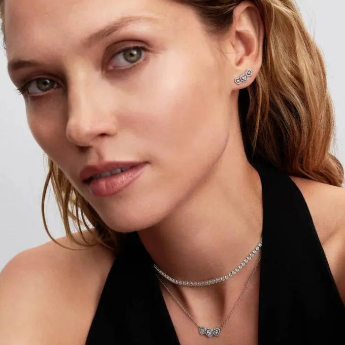 Woman wearing the Pandora Halo Heart Trilogy Stud Earrings in sterling silver with a matching necklace.