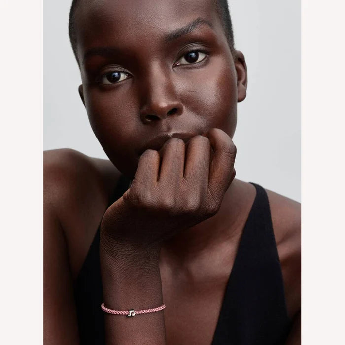 Woman wearing a pink bracelet with a mini music note charm