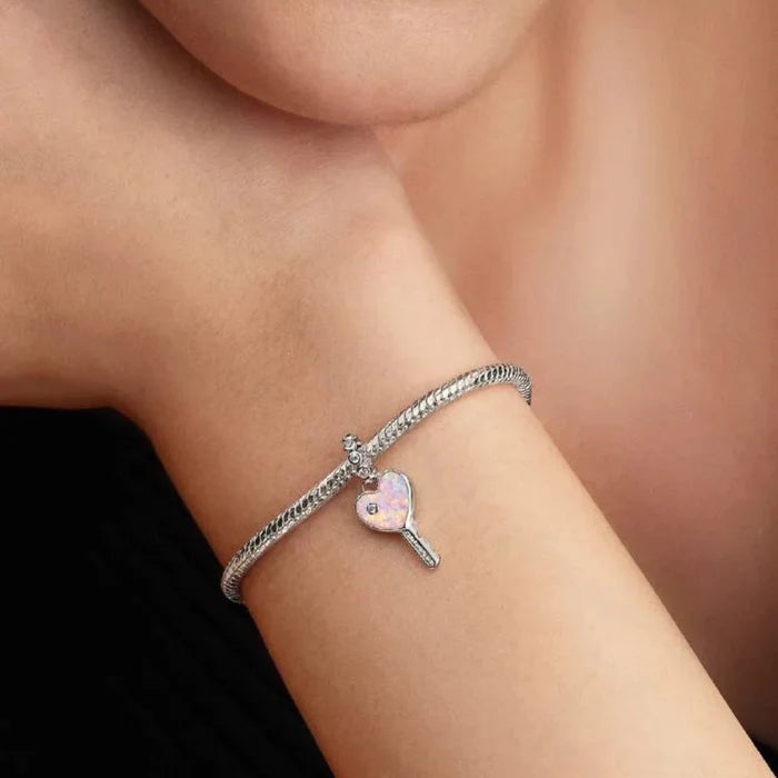 Silver bracelet with a heart-shaped charm worn on a wrist, close-up of face.