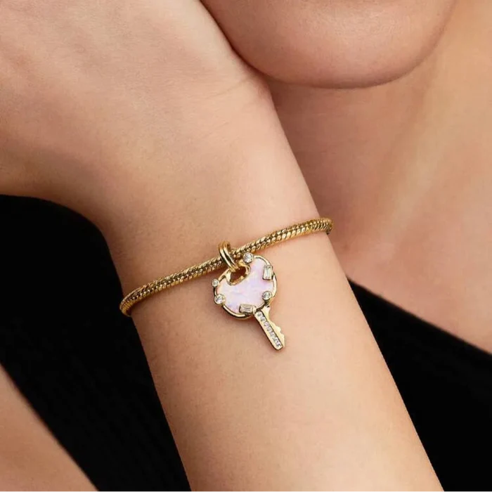 Gold bracelet with a heart-shaped charm worn by a person against a black background